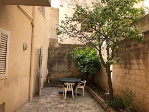 een tafel en twee stoelen en een boom in een steegje bij Casa Icaro in Marinella di Selinunte