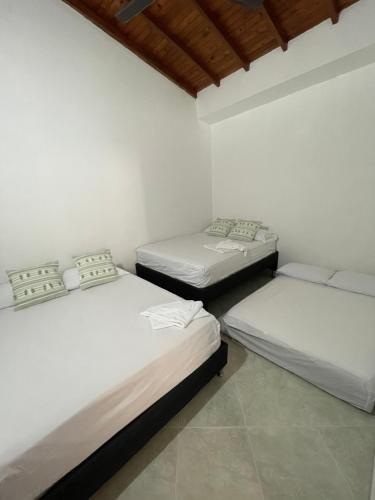 Apartamento de Descanso - Doradal في Doradal: ثلاثة أسرة في غرفة بجدران بيضاء