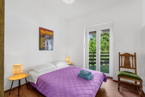 1 dormitorio con 1 cama de color púrpura y 1 silla en Apartments Villa Verde, en Novigrad Istria