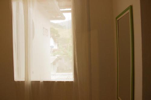 a window with a white curtain in a room at Pousada no Sana Donna Leda in Sana