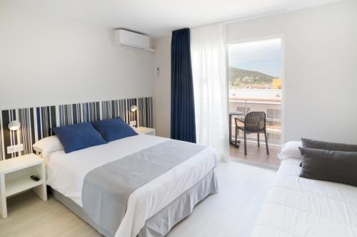 a white bedroom with a bed and a balcony at Ibersol Sorra d'Or in Malgrat de Mar