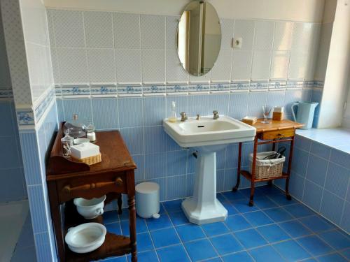a blue tiled bathroom with a sink and a mirror at La ferme des douceurs in Cervon