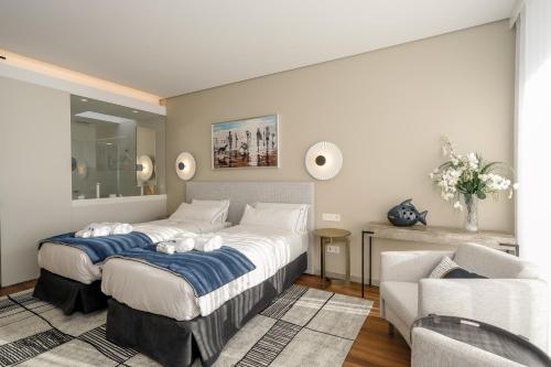 a bedroom with two beds and a couch and a chair at Villa Paladina in Foz do Arelho