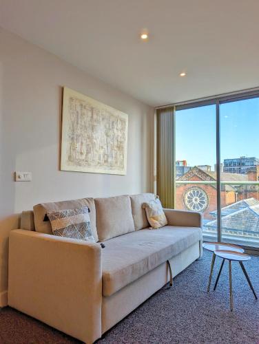 uma sala de estar com um sofá e uma grande janela em Viva 1 Bed Apartment Birmingham City Centre em Birmingham