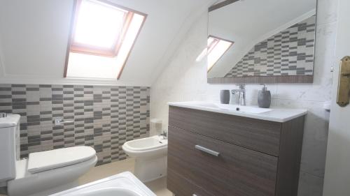 a bathroom with a sink and a toilet and a window at Ático Laxe Grande in A Guarda