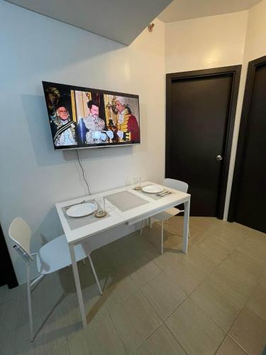 a white table with a tv hanging on a wall at 2 cozy bedroom fully furnished apartment for rent in Manila