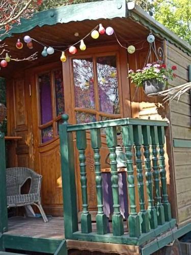 une petite maison avec une balustrade verte sur une terrasse couverte dans l'établissement Roulotte des Alpilles, à Maussane-les-Alpilles