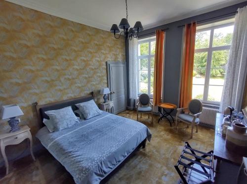 a bedroom with a bed and chairs and windows at Maison Grandsire Logis de Charme in Saint-Léonard