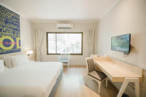 1 dormitorio con cama, escritorio y ventana en The Park Hotel, en Phitsanulok