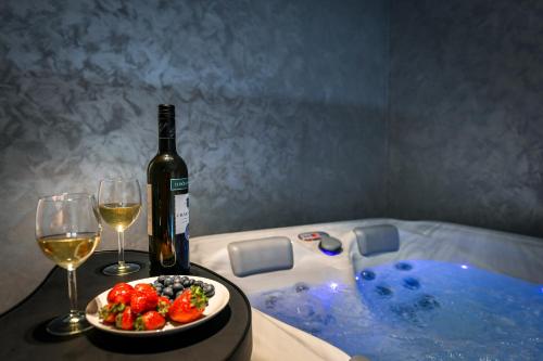 a bottle of wine and a plate of fruit next to a hot tub at Kuća za odmor Bubamara in Ravna Gora