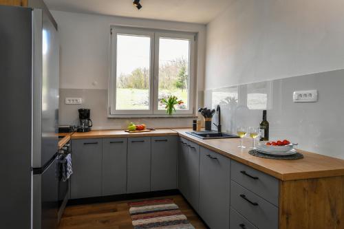 a kitchen with white cabinets and a wooden counter top at Kuća za odmor Bubamara in Ravna Gora