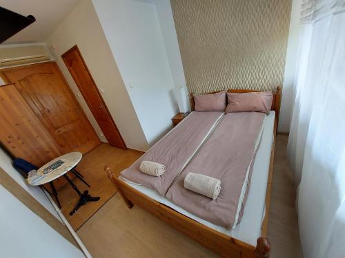 a bedroom with a bed with pink sheets and a chair at Palma Vendégház in Szeged