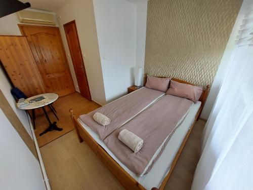 a small bedroom with a bed with pink sheets at Palma Vendégház in Szeged