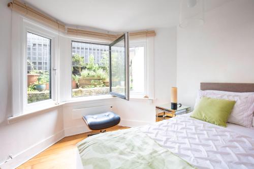 a bedroom with a bed and two windows at Modern flat with KING bed, garden & outdoor dining in London