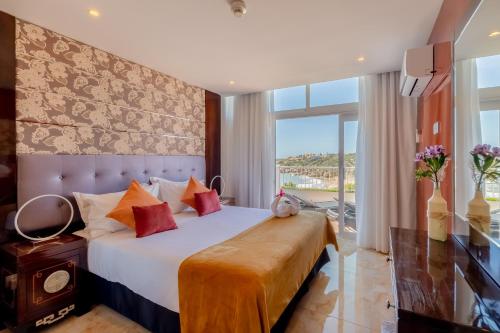 ein Schlafzimmer mit einem großen Bett und einem großen Fenster in der Unterkunft Monicca Collection Suites and Residences in Albufeira