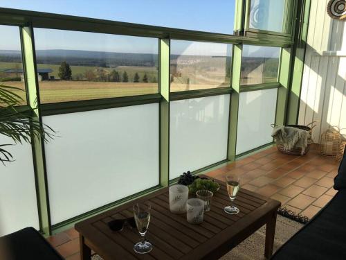 a screened in porch with a table and glasses of wine at Gemütliches Apartment mit wundervollem Weitblick in Löffingen