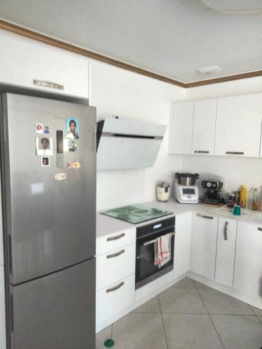 una cucina con frigorifero in acciaio inossidabile e armadietti bianchi di Bulle d oxygène a Rubelles