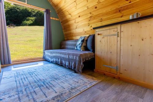 a couch in a tiny house with a window at The Woolpack Glamping in Maidstone