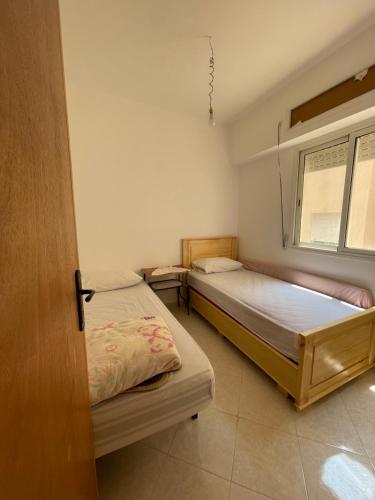 1 dormitorio con 2 camas y ventana en Economic Apartment Alhoceima WIFI, en Alhucemas