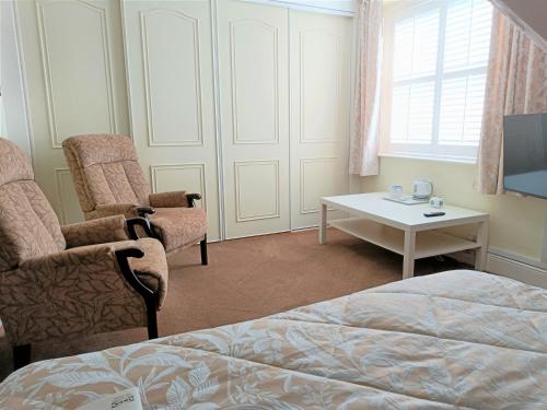 a bedroom with a bed and two chairs and a table at Granby House in Llandudno