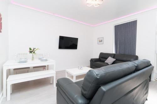 a living room with a black leather couch and a table at Monroe House Leeds in Leeds