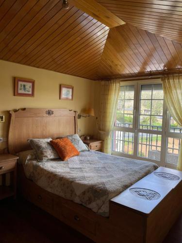sypialnia z dużym łóżkiem i drewnianym sufitem w obiekcie Cabo de Veiga w mieście Trabada