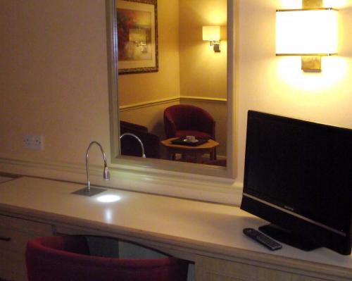a hotel room with a desk with a television and a mirror at Best Western Ipswich Hotel in Ipswich