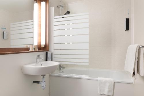 a white bathroom with a sink and a window at Campanile Dole in Dole