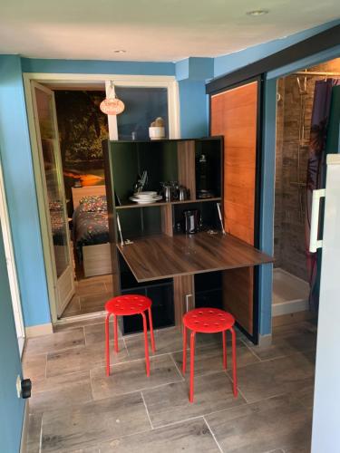 a kitchen with two red stools next to a counter at Dépendance dans le jardin in Franqueville-Saint-Pierre