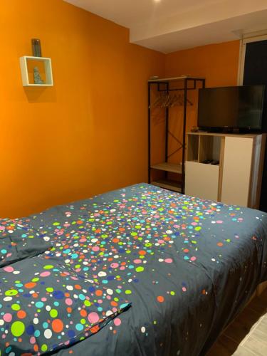 a bed with polka dots on it in a room at Dépendance dans le jardin in Franqueville-Saint-Pierre