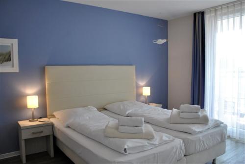 2 camas num quarto com paredes azuis e 2 candeeiros em Apartmenthaus Hafenspitze, Ap 29 "Heimathafen 29", Blickrichtung InnenstadtBinnenhafen - a72349 em Eckernförde