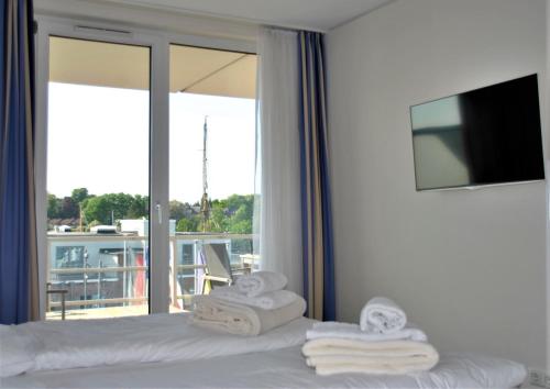 a hotel room with towels on a bed with a balcony at Apartmenthaus Hafenspitze, Ap 29 "Heimathafen 29", Blickrichtung InnenstadtBinnenhafen - a72349 in Eckernförde
