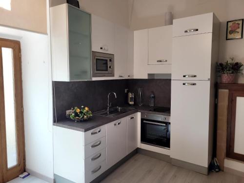 a kitchen with white cabinets and a sink at Visiale guest house in Spoleto