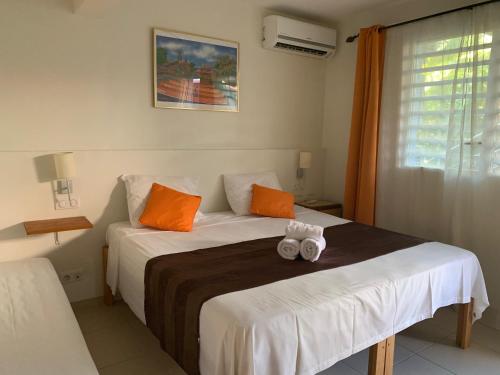 a bedroom with two beds with orange and white pillows at Hôtel DOUCE VAGUE in Sainte-Luce