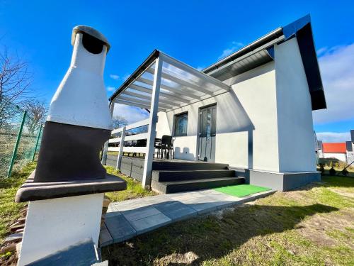 a small white house with a black and white structure at Apartament na Ogrodowej - 2 sypialnie, ogród, taras, parking in Trzęsacz