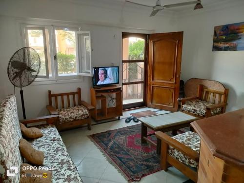 a living room with a tv and a couch and chairs at الساحل الشمالي in El Alamein