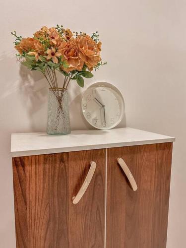 a clock and a vase with flowers on a cabinet at [Starry x DELUX] 8-10pax *free Netflix access in Masai