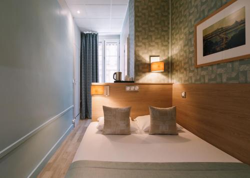 a hotel room with a bed with two pillows at Hôtel du Dauphin in Lyon