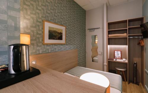 a small room with a bed and a desk at Hôtel du Dauphin in Lyon