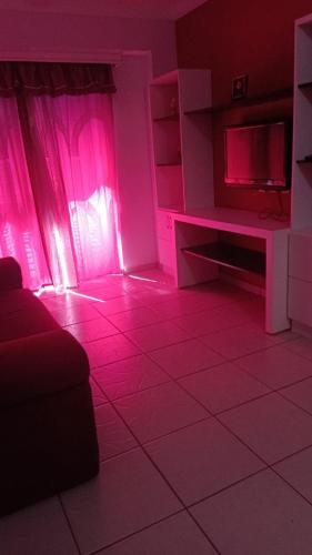 een woonkamer met roze verlichting en een televisie bij Apart Flat Aguas da Serra in Rio Quente