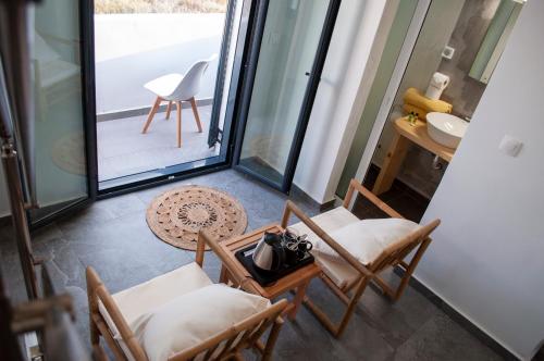 a room with chairs and a table and a balcony at Sun Springs Suites in Kamari