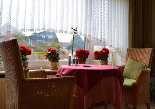 einen Tisch mit Blumen vor einem Fenster in der Unterkunft Haus Ohio Garni in Borkum