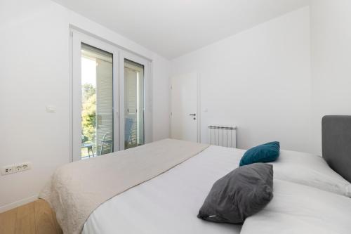 a white bedroom with a large bed and a window at LuSea Apartment in Zadar