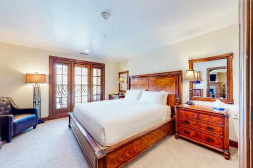 a bedroom with a bed and a chair and a mirror at Avon Peaks, Apt 416 in Avon