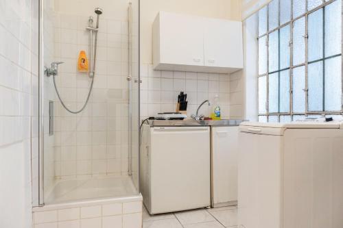 ein weißes Bad mit einer Dusche und einer Waschmaschine in der Unterkunft Convenient 1BR Apartment in the Heart of Vienna in Wien