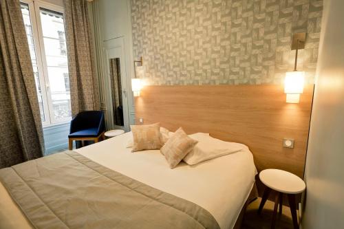 a hotel room with a bed and a wooden headboard at Hôtel du Dauphin in Lyon