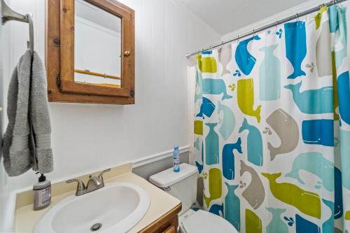 a bathroom with a sink and a toilet with a shower curtain at Sunny Daze KDH by Village Reality in Kill Devil Hills
