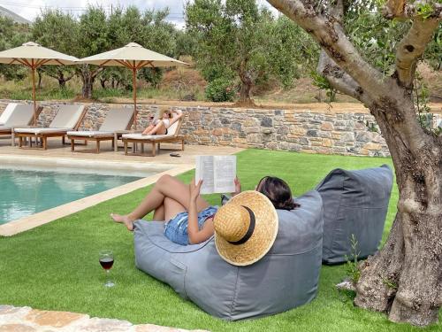 a woman laying on a bean bag chair reading a book at Drosia Villa Private Nature Getaway! in Plakias