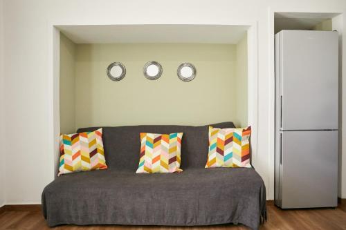 a living room with a couch and two clocks on the wall at Mosaic Luxury House in Chios