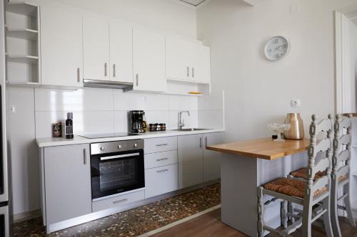 a kitchen with white cabinets and a counter with a table at Mosaic Luxury House in Chios